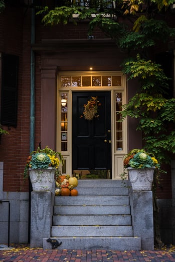 front door to brick building with pumpkins and fall decorations on the stairs